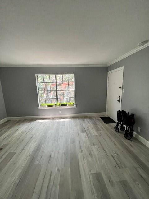 unfurnished living room featuring light wood-type flooring and crown molding