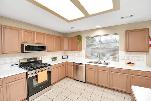 kitchen with decorative backsplash, stainless steel appliances, sink, light tile patterned floors, and light brown cabinets