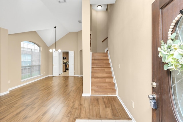 foyer with wood-type flooring, vaulted ceiling, and a chandelier