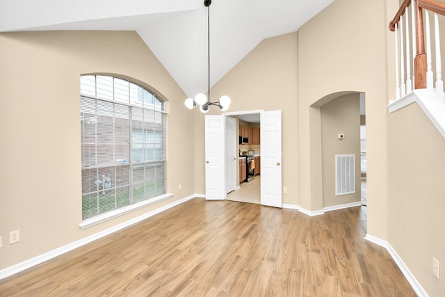 unfurnished dining area with high vaulted ceiling, light hardwood / wood-style flooring, a healthy amount of sunlight, and a notable chandelier