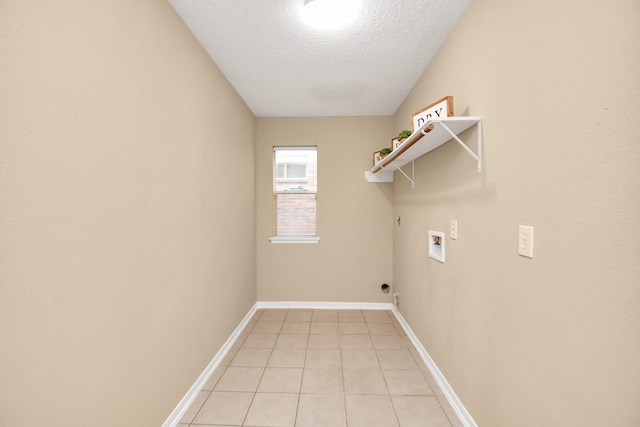 clothes washing area with hookup for a gas dryer, light tile patterned floors, washer hookup, and a textured ceiling