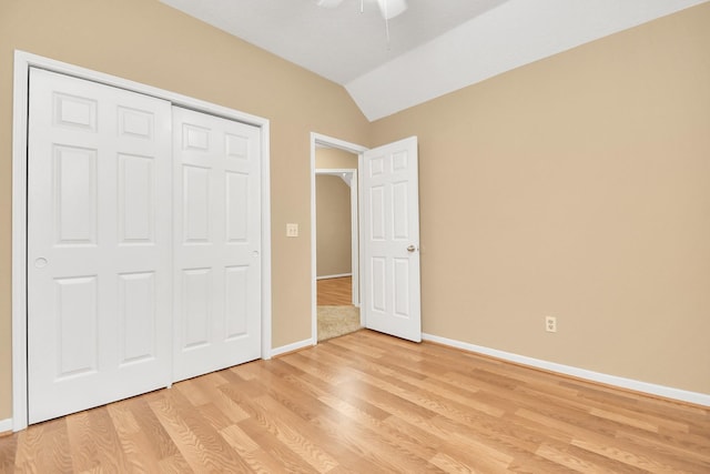 unfurnished bedroom with ceiling fan, vaulted ceiling, light hardwood / wood-style flooring, and a closet