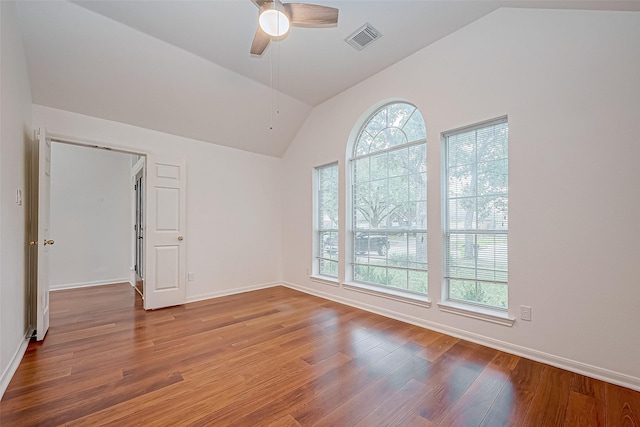 empty room featuring ceiling fan, hardwood / wood-style floors, a healthy amount of sunlight, and vaulted ceiling