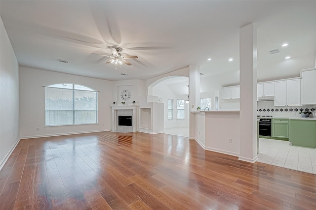 unfurnished living room featuring a high end fireplace, wood-type flooring, and ceiling fan