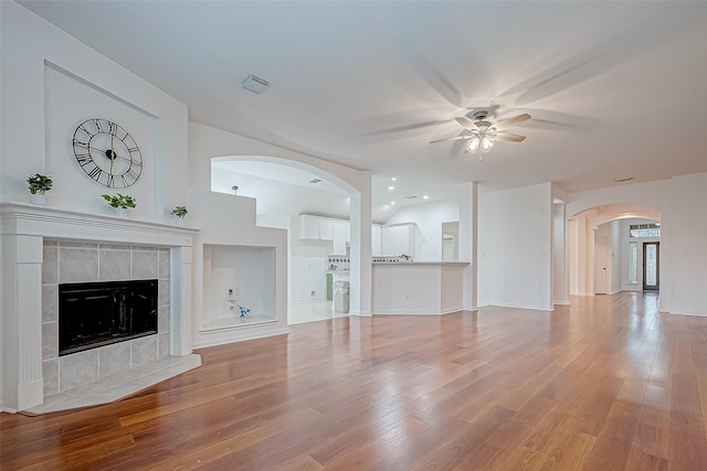 unfurnished living room with a tile fireplace, hardwood / wood-style flooring, and ceiling fan