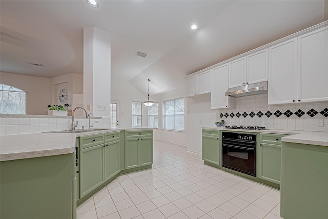 kitchen featuring decorative backsplash, vaulted ceiling, sink, white cabinets, and black oven