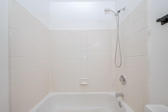 bathroom featuring toilet and tiled shower / bath