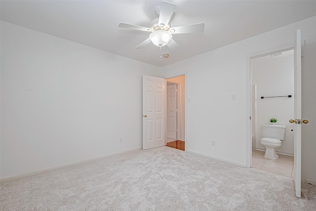 unfurnished bedroom featuring ceiling fan, light carpet, and ensuite bath