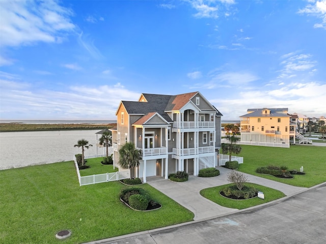 view of front of property featuring a front yard, a balcony, a garage, and a water view