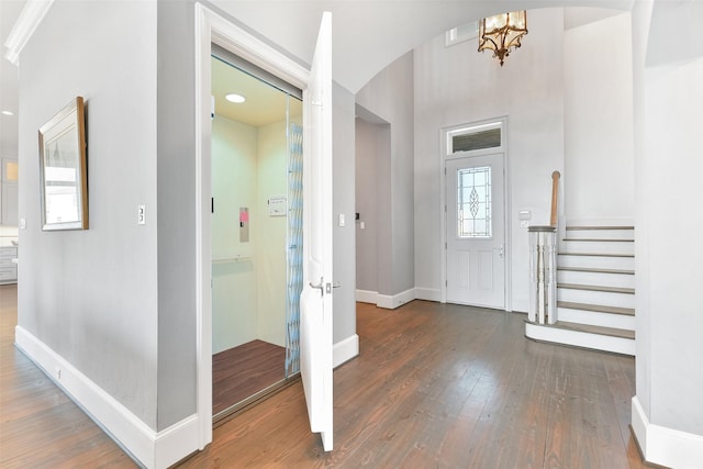 foyer entrance featuring a wealth of natural light, dark wood-type flooring, and a notable chandelier