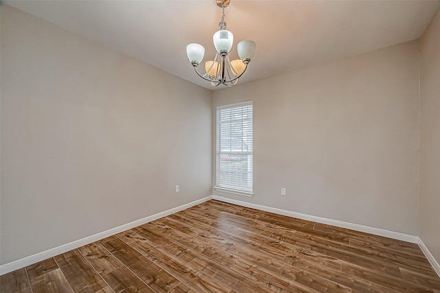 spare room featuring a chandelier and hardwood / wood-style flooring