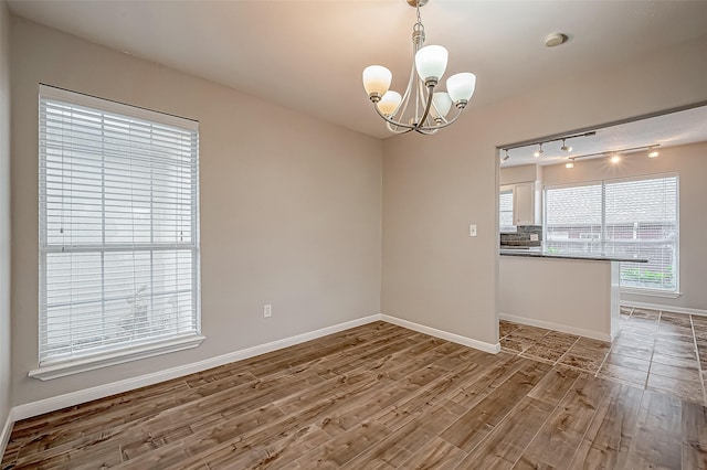 unfurnished dining area featuring hardwood / wood-style flooring and an inviting chandelier