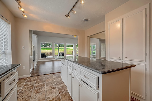 kitchen with white cabinetry, a kitchen island, dark stone counters, and a textured ceiling