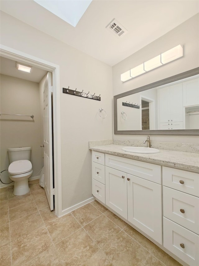 bathroom featuring a skylight, vanity, and toilet