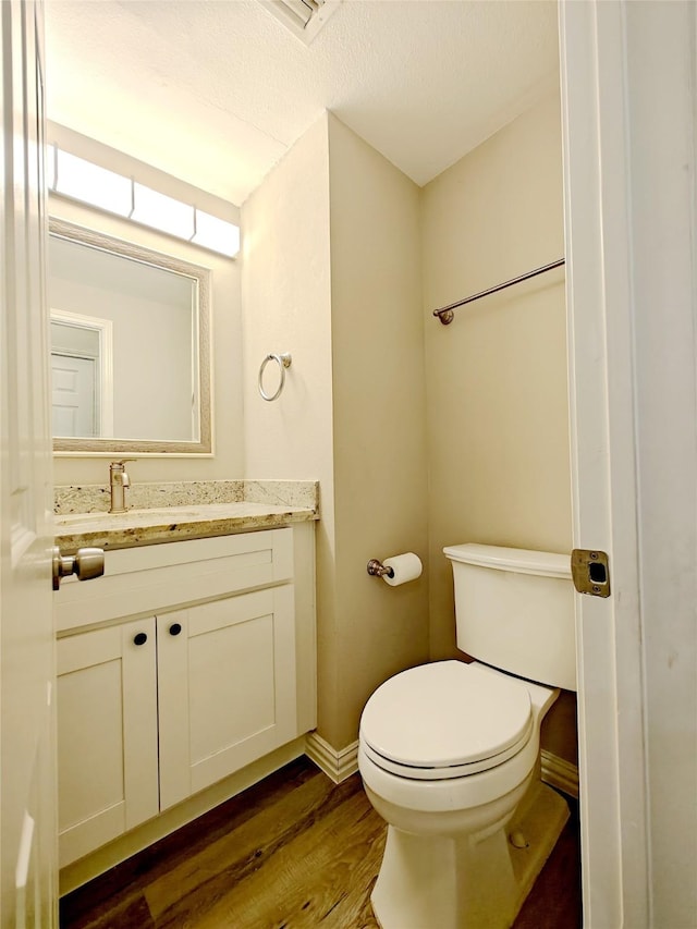 bathroom featuring toilet, vanity, a textured ceiling, and hardwood / wood-style flooring