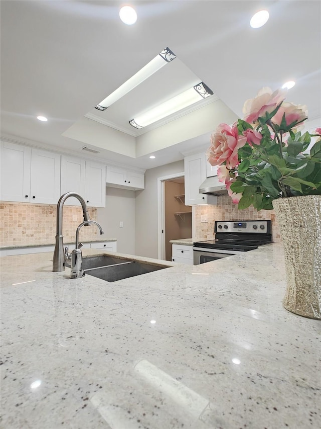 kitchen with decorative backsplash, a tray ceiling, stainless steel electric stove, sink, and white cabinets