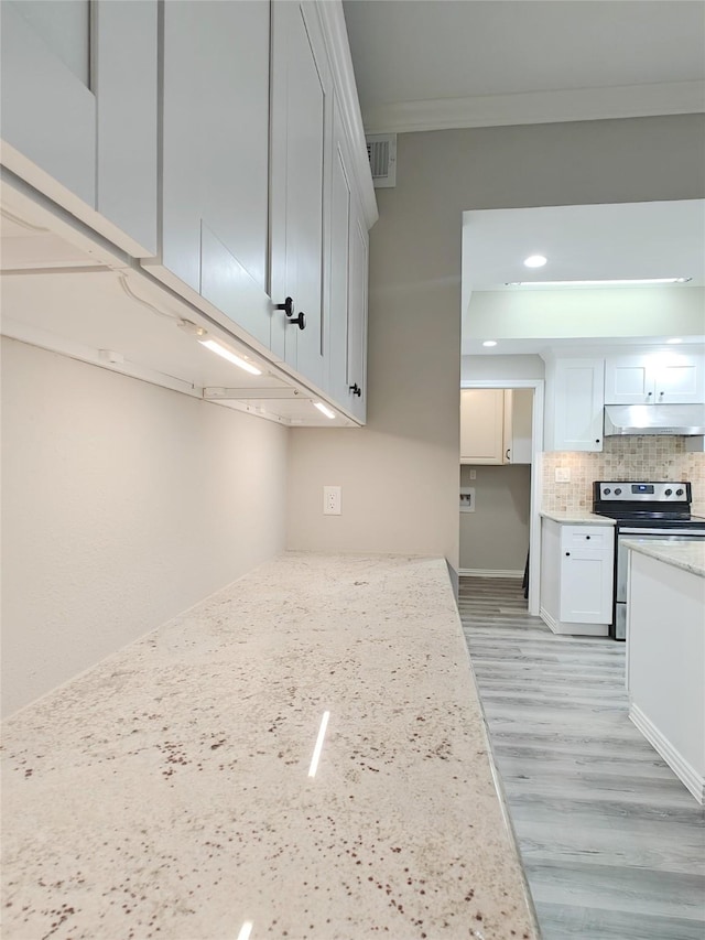 kitchen with backsplash, crown molding, electric range, light stone countertops, and white cabinetry