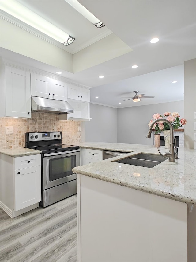 kitchen featuring stainless steel electric stove, kitchen peninsula, sink, light stone counters, and white cabinetry