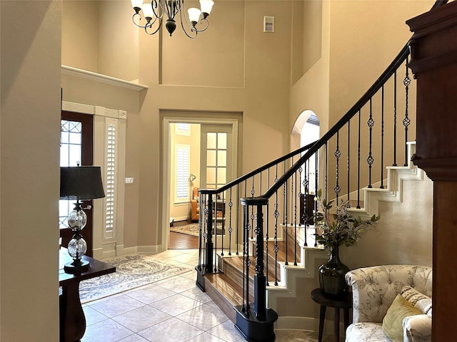 tiled foyer entrance with a towering ceiling and an inviting chandelier