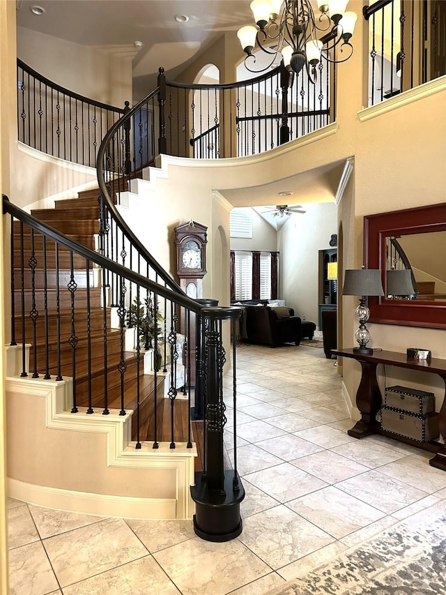 stairs featuring tile patterned flooring, a towering ceiling, and ceiling fan with notable chandelier