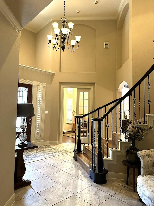 foyer entrance with ornamental molding, a towering ceiling, and a notable chandelier