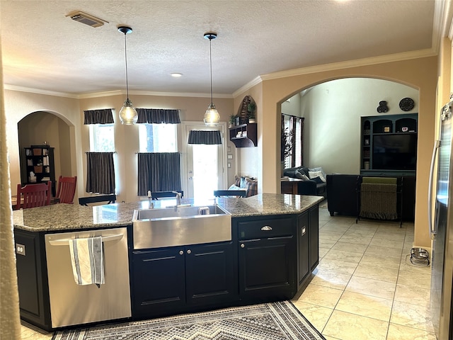 kitchen with sink, stainless steel appliances, hanging light fixtures, and an island with sink