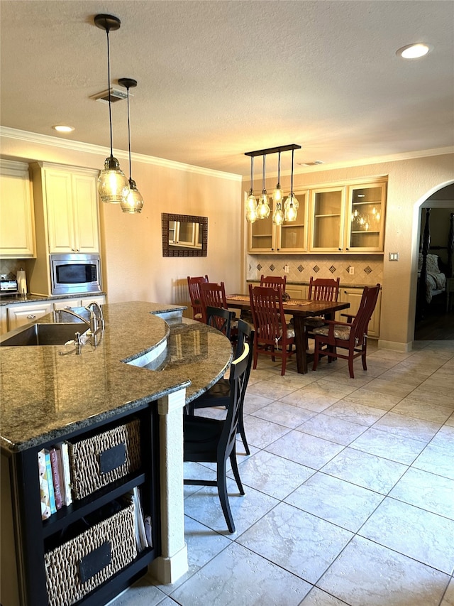 kitchen featuring cooktop, decorative backsplash, stainless steel microwave, and dark stone counters