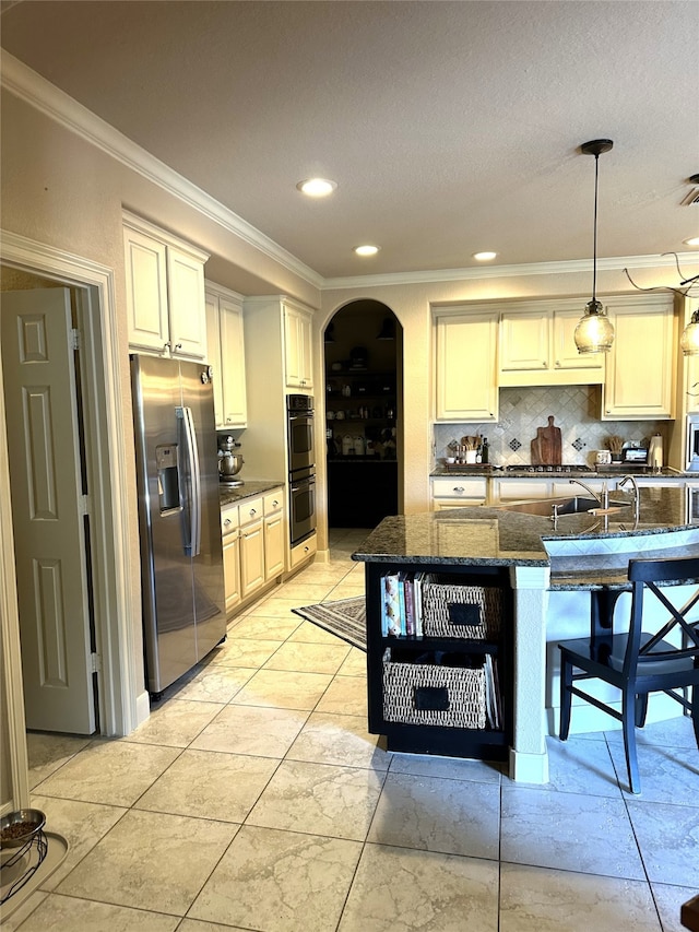 kitchen featuring pendant lighting, dark stone counters, a kitchen breakfast bar, appliances with stainless steel finishes, and tasteful backsplash