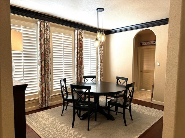 dining area featuring hardwood / wood-style floors, a textured ceiling, and ornamental molding