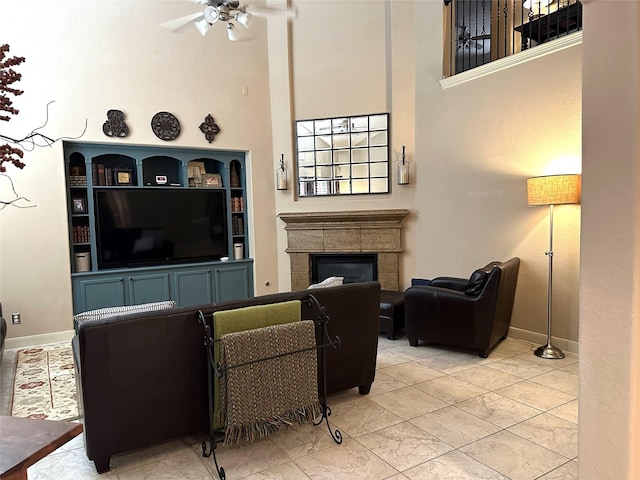 living room featuring ceiling fan, a fireplace, and a high ceiling