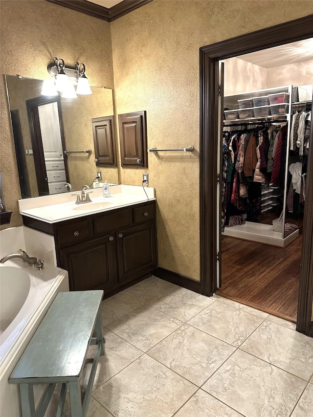 bathroom featuring a bathing tub, vanity, crown molding, and tile patterned flooring