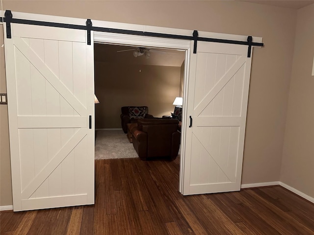 hallway featuring a barn door and dark wood-type flooring