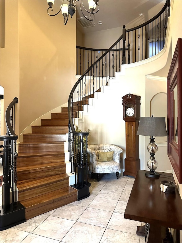 stairway featuring tile patterned floors, a towering ceiling, and a chandelier