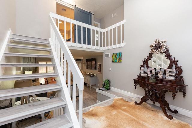 stairway with hardwood / wood-style floors and a towering ceiling