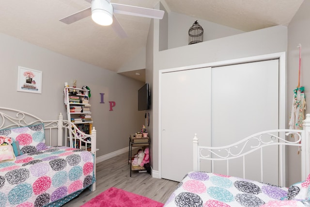 bedroom with ceiling fan, light wood-type flooring, a closet, and lofted ceiling