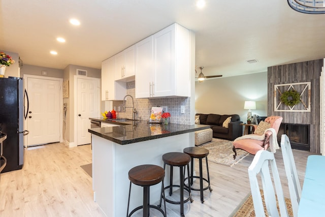 kitchen with sink, fridge, white cabinetry, kitchen peninsula, and a breakfast bar