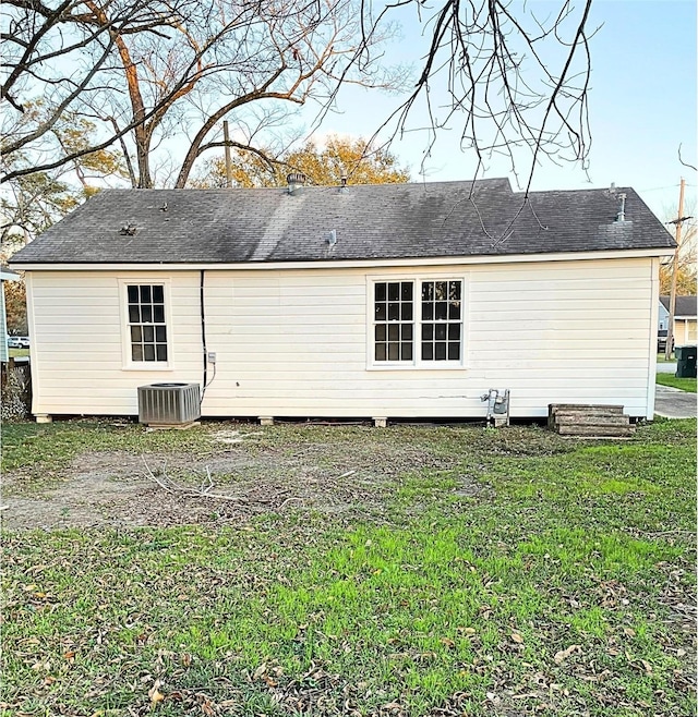 rear view of property with central AC and a lawn