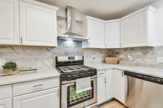 kitchen featuring white cabinets, appliances with stainless steel finishes, tasteful backsplash, and wall chimney exhaust hood