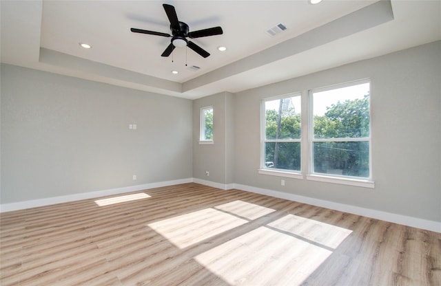 spare room with ceiling fan, a raised ceiling, and light hardwood / wood-style flooring