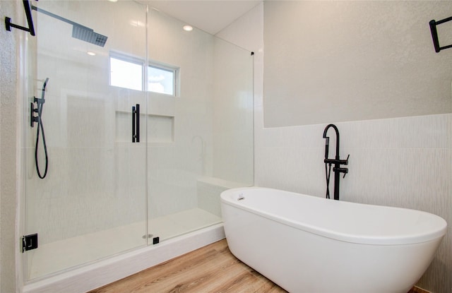 bathroom with shower with separate bathtub, wood-type flooring, and tile walls