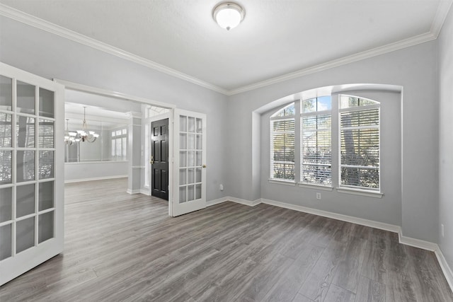 spare room with hardwood / wood-style flooring, french doors, crown molding, and an inviting chandelier