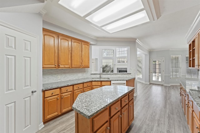 kitchen featuring light stone countertops, sink, a kitchen island, and ornamental molding