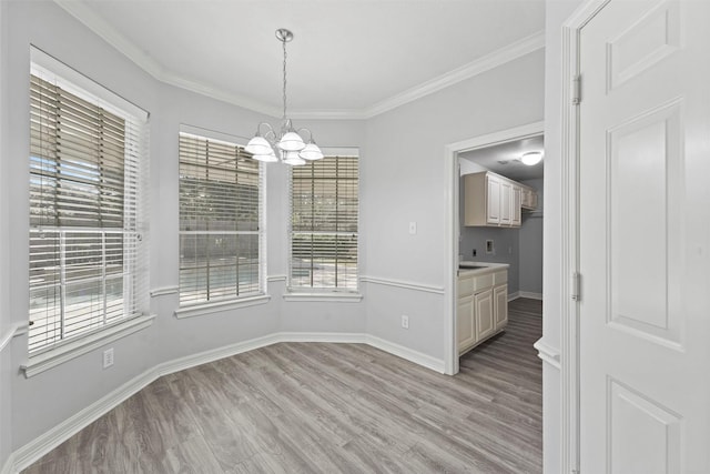 unfurnished dining area featuring light hardwood / wood-style floors, ornamental molding, and an inviting chandelier