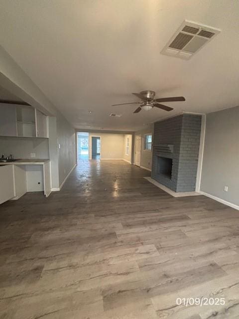 unfurnished living room with ceiling fan, hardwood / wood-style floors, sink, and a brick fireplace