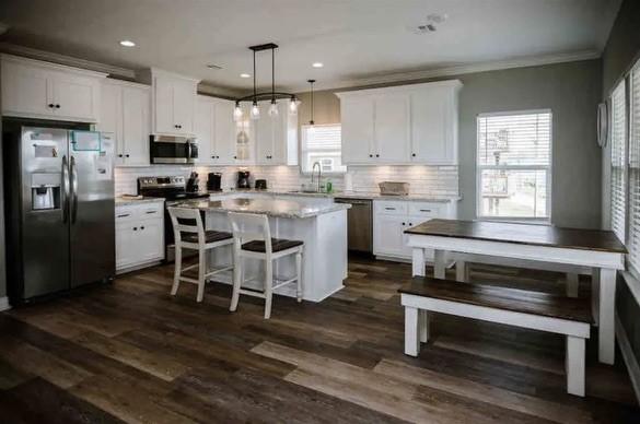 kitchen with white cabinets, appliances with stainless steel finishes, dark hardwood / wood-style floors, and hanging light fixtures