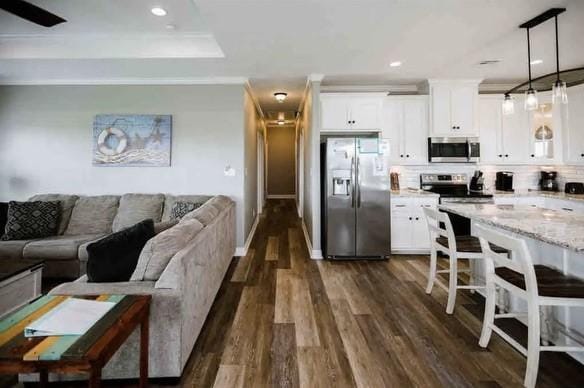 kitchen featuring light stone counters, hanging light fixtures, white cabinets, and stainless steel appliances