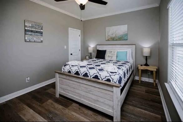 bedroom with ceiling fan, dark hardwood / wood-style flooring, and ornamental molding