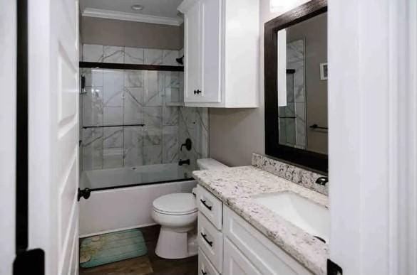 full bathroom featuring vanity, toilet, combined bath / shower with glass door, and ornamental molding