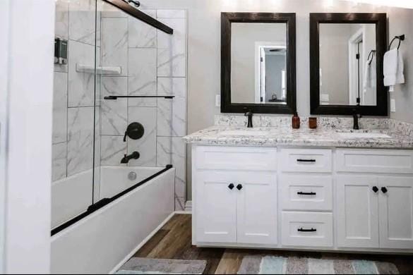 bathroom with vanity, wood-type flooring, and bath / shower combo with glass door