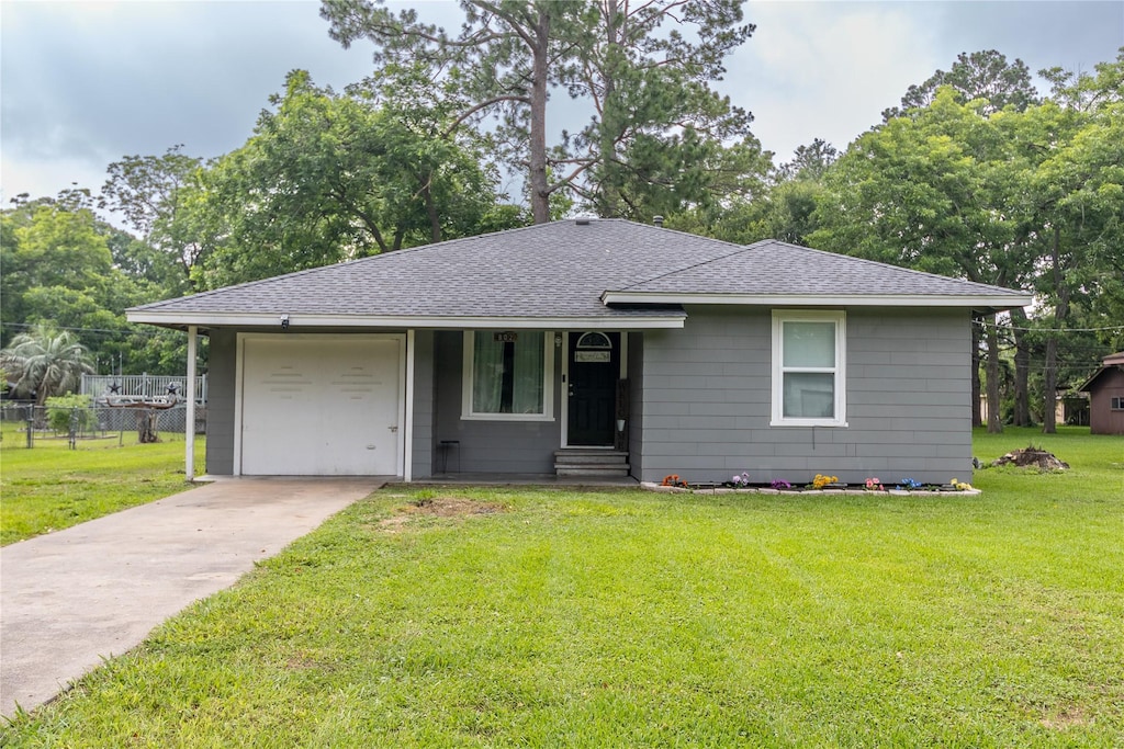 view of front of property with an attached garage, roof with shingles, concrete driveway, and a front yard